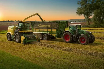 Řezačka Krone plní přívěs za traktorem při sklizni píce.