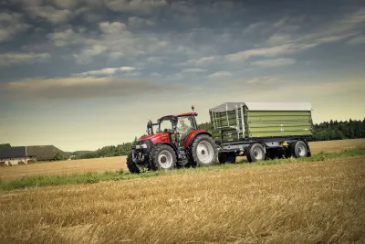Traktor Case IH Farmall C s přívěsem na louce.