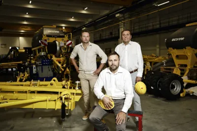 Tři představitelé společnosti BEDNAR FMT stojí u žlutých zemědělských strojů.