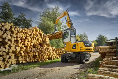 Manipulační stroj Liebherr ukládá kmeny na hromadu.