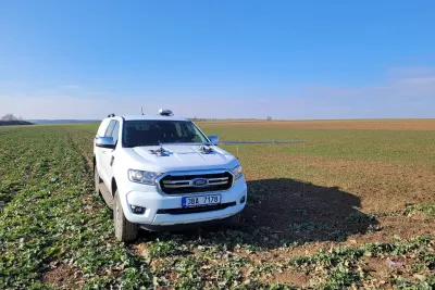 Bílý automobil Ford s anténami navigace na poli
