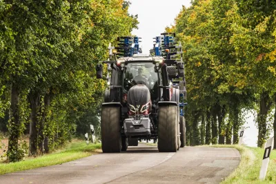 Traktor Valtra na silnici mezi stromy