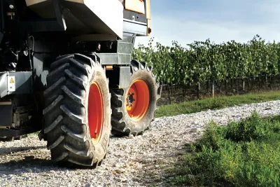 Pneumatiky zemědělského stroje na kamenité cestě vedle vinice