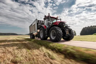 Červený traktor Case IH Optum s přívěsem na silnici