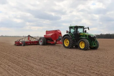 Zelený traktor s červeným secím strojem Horsch na poli