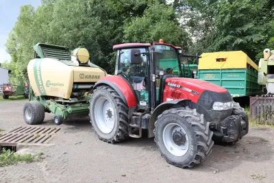 Červený traktor Case IH s lisem Krone na farmě
