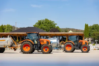 Dva oranžové traktory Kubota M7 v jezdeckém areálu