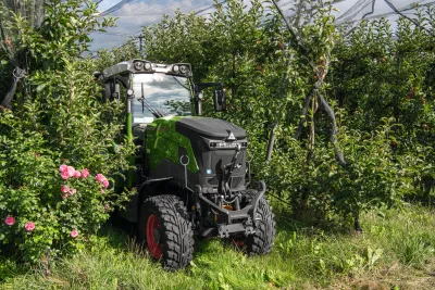 Zelený elektrický traktor Fendt mezi ovocnými stromy