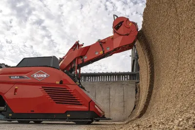 Červený autonomní krmný vůz Kuhn Aura odebírá krmivo ze siláže
