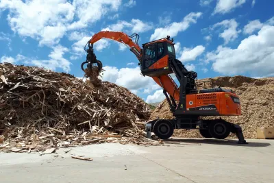 Oranžový manipulátor Develon překládá dřevní štěpku