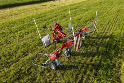 Červený obraceč Massey Ferguson na louce