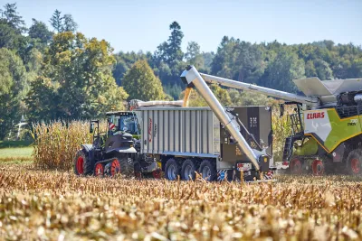 Kombajn Claas při sklizni kukuřice vedle návěsu Fliegl