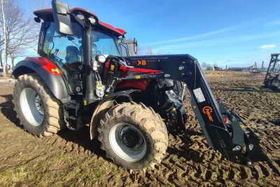 Červený traktor Case IH s čelním nakladačem stojí na poli