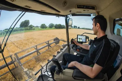 Řidič za volantem sklízecí mlátičky při práci na poli.