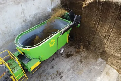 Pohled shora na zelený míchací krmný vůz u sila.