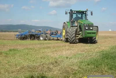 John Deere s nářadím Köckerling na poli.