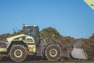 Nakladač Volvo LX1 s naplněnou lžící na skládce.