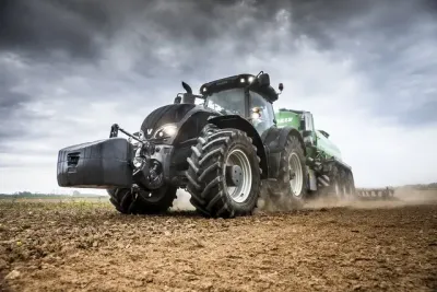 Tmavý traktor Valtra pracuje na poli