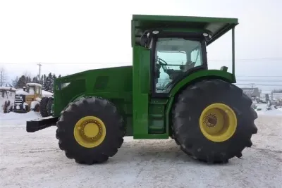Boční pohled na lesní traktor John Deere 7310R na sněhu.