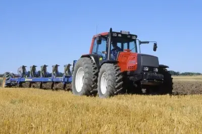 Červený traktor Valmet při orbě na poli